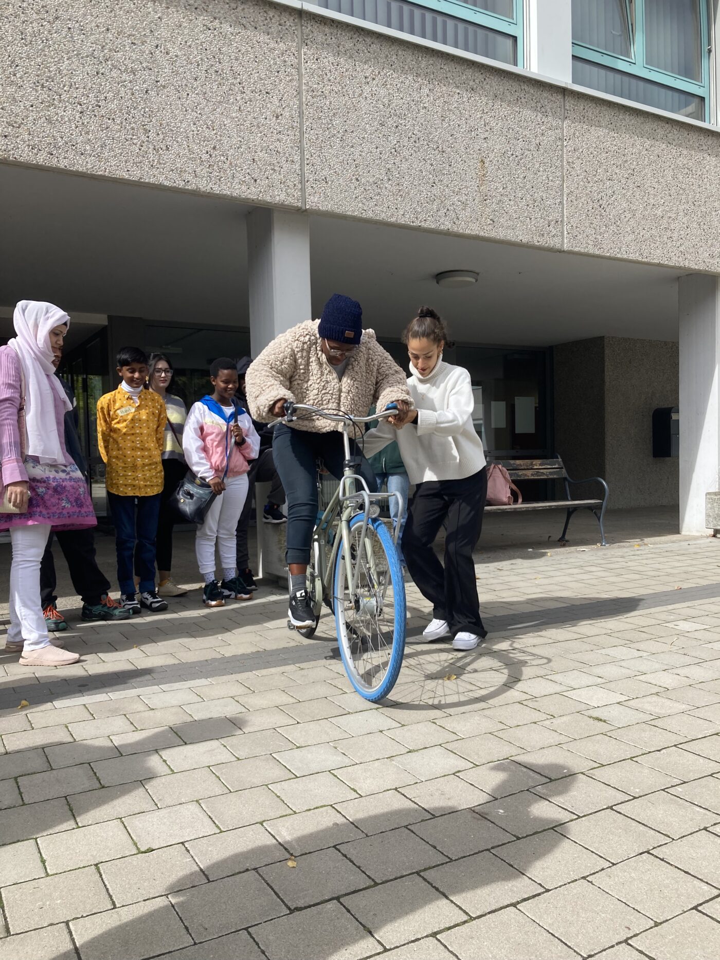 Jugendliche auf Fahrrad, wobei andere Jugendliche hilft