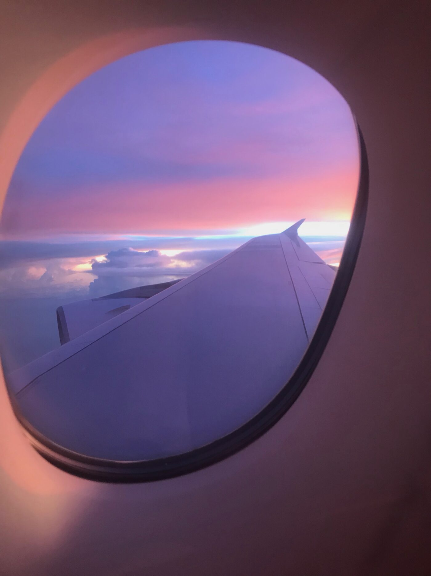 Bild: Ein aus dem Flugzeug heraus fotografierter Sonnenuntergang über den Wolken; Titelbild für den Blogbeitrag: Aller guten Dinge sind 3, Wie mich eine Reise in drei Länder mein Kulturverständnis hinterfragen ließ
