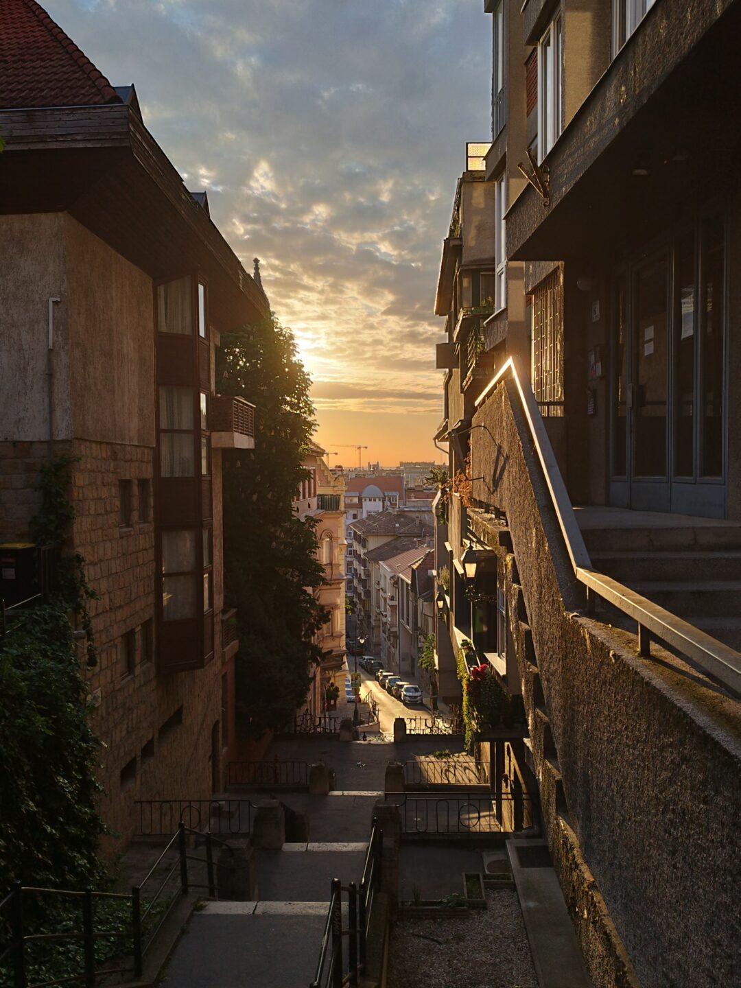 Auf dem Bild sieht man eine enge Gasse, durch welche man auf die Stadt blicken kann.