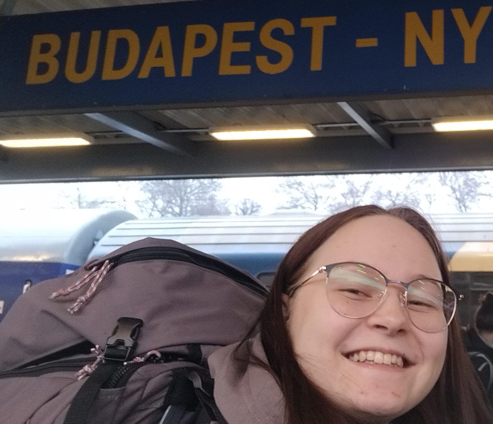 Auf dem Bild sieht man eine Peron. Im Hintergrund hängt ein Schild auf dem "Budapest" steht.