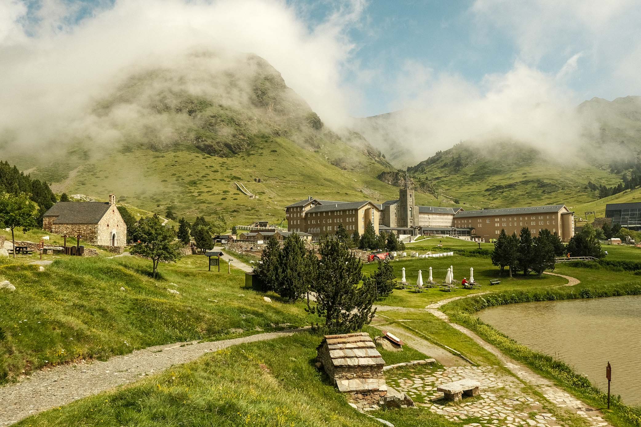 "Living La Vida Loca" in Barcelona 9 IMG 8368 Mountain landscape with a large building, a small stone house and a lake.